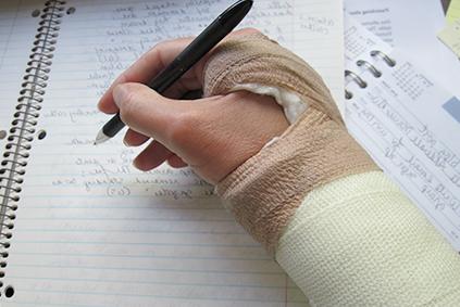 Hand in cast holding a pencil